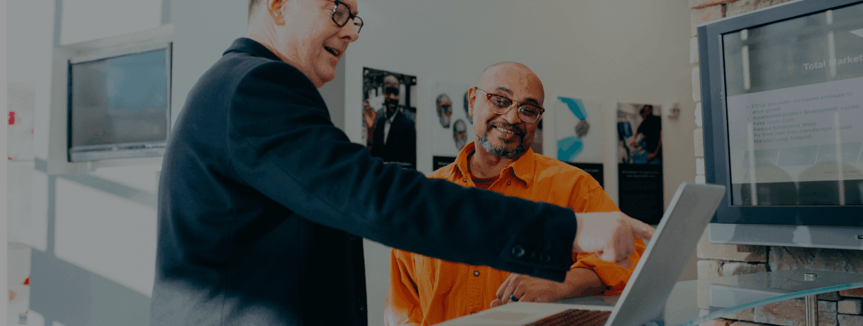 Two business men looking at a laptop screen together, signifying working collaboration