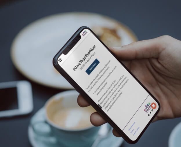 A man is viewing the UpTogether site in his mobile phone, where he can apply for Covid relief through UpTogether