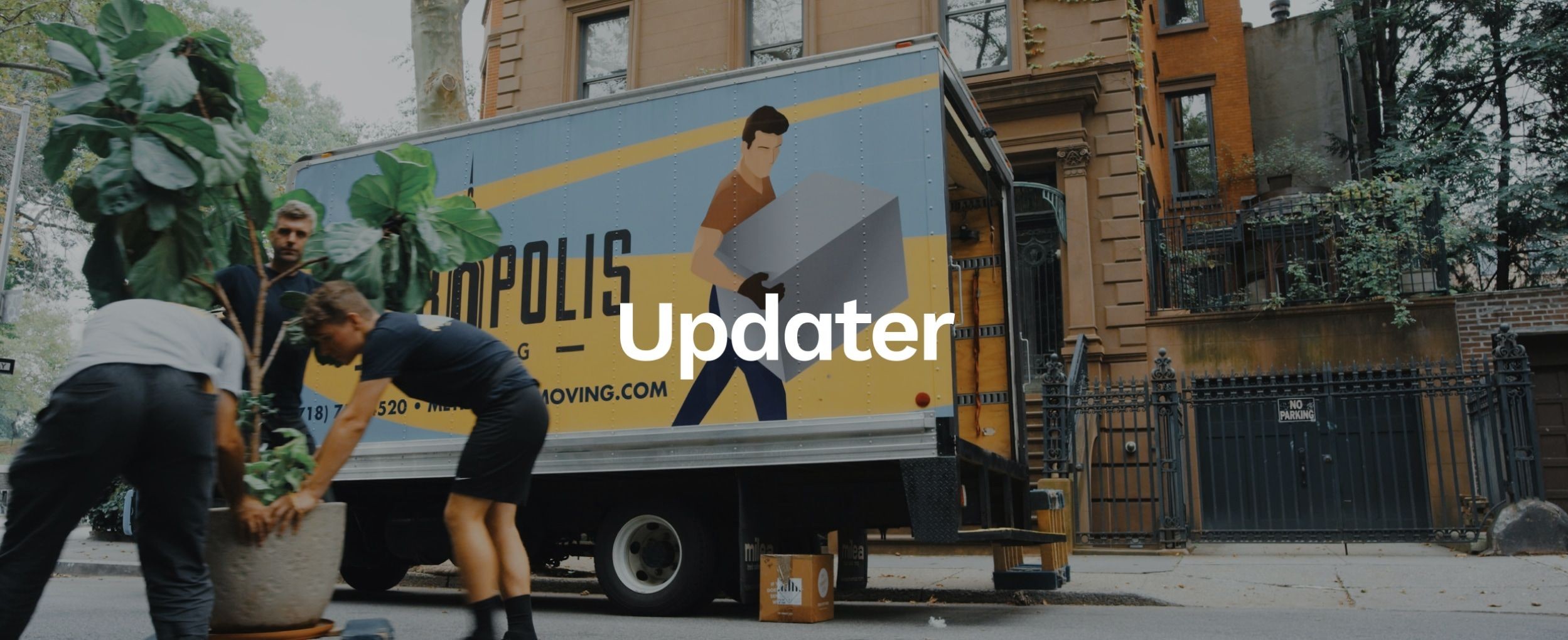 Three men move items out of a moving van on an urban city street. The Updater logo appears over the image.