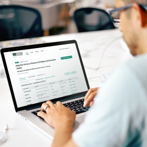 A man in an office setting views a project opportunity on We the Action application on his laptop